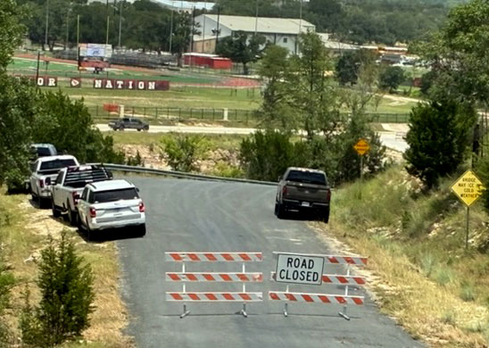 Road Closed orange-and-white barricades are shown at the TX39 entrance to Cade Loop Bridge.